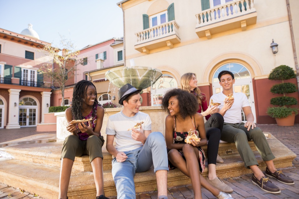 Teens enjoying pizza by the harbor-piazza fountain at Loews Portofino Bay Hotel.