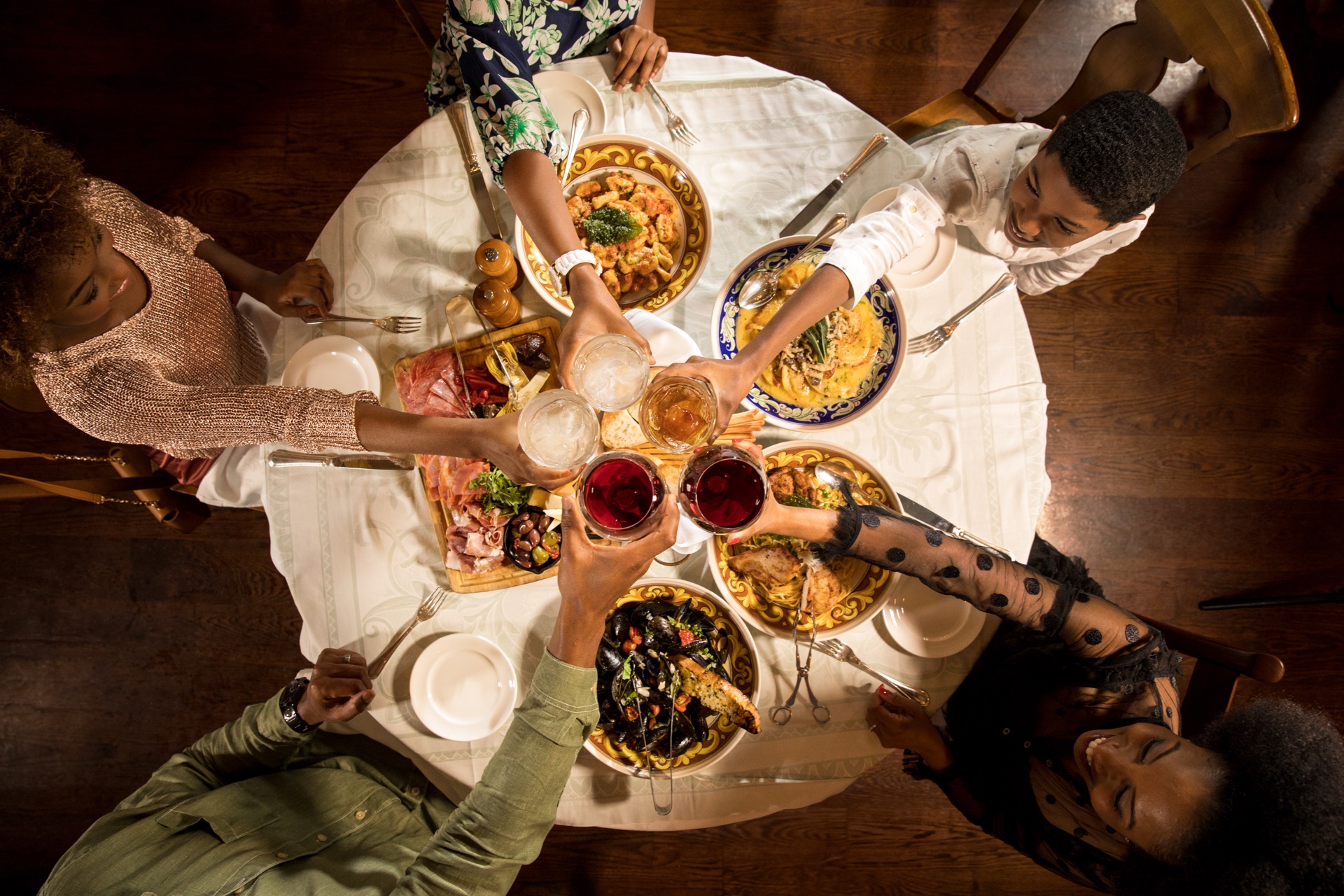 Family clinking glasses over a family-style Italian dinner at Mama Della's, Loews Portofino Bay Hotel.